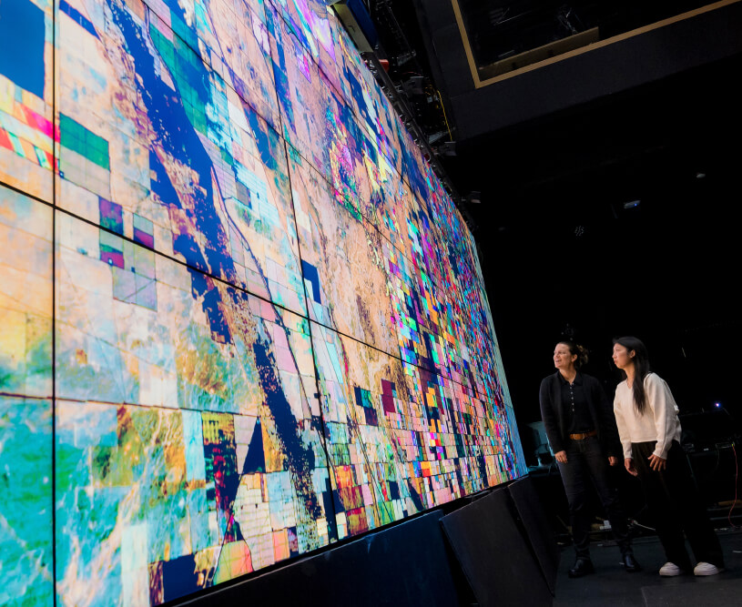 Professor and student looking at a giant wall of screens